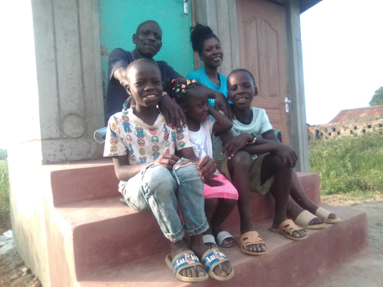 Meshack and family plus Vincent on the steps of their new composting toilet and bathroom